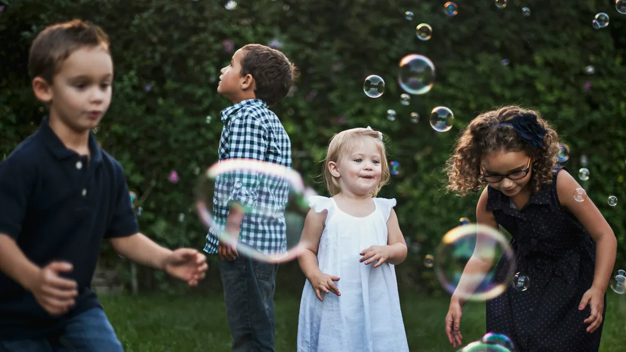 Quatro crianças brincando com bolhas de sabão em um jardim